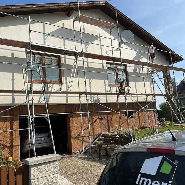 Ein Haus wird abgerissen und neu aufgebaut, mit Baustellenmaterialien und Maschinen im Vordergrund.