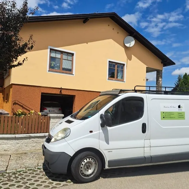 Ein Van steht vor einem Wohnhaus mit einem einladenden Eingangsbereich und Blumenbeeten.