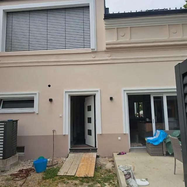 Ein im Bau befindliches Haus mit einem großen Fenster, das den Fortschritt der Konstruktion zeigt.