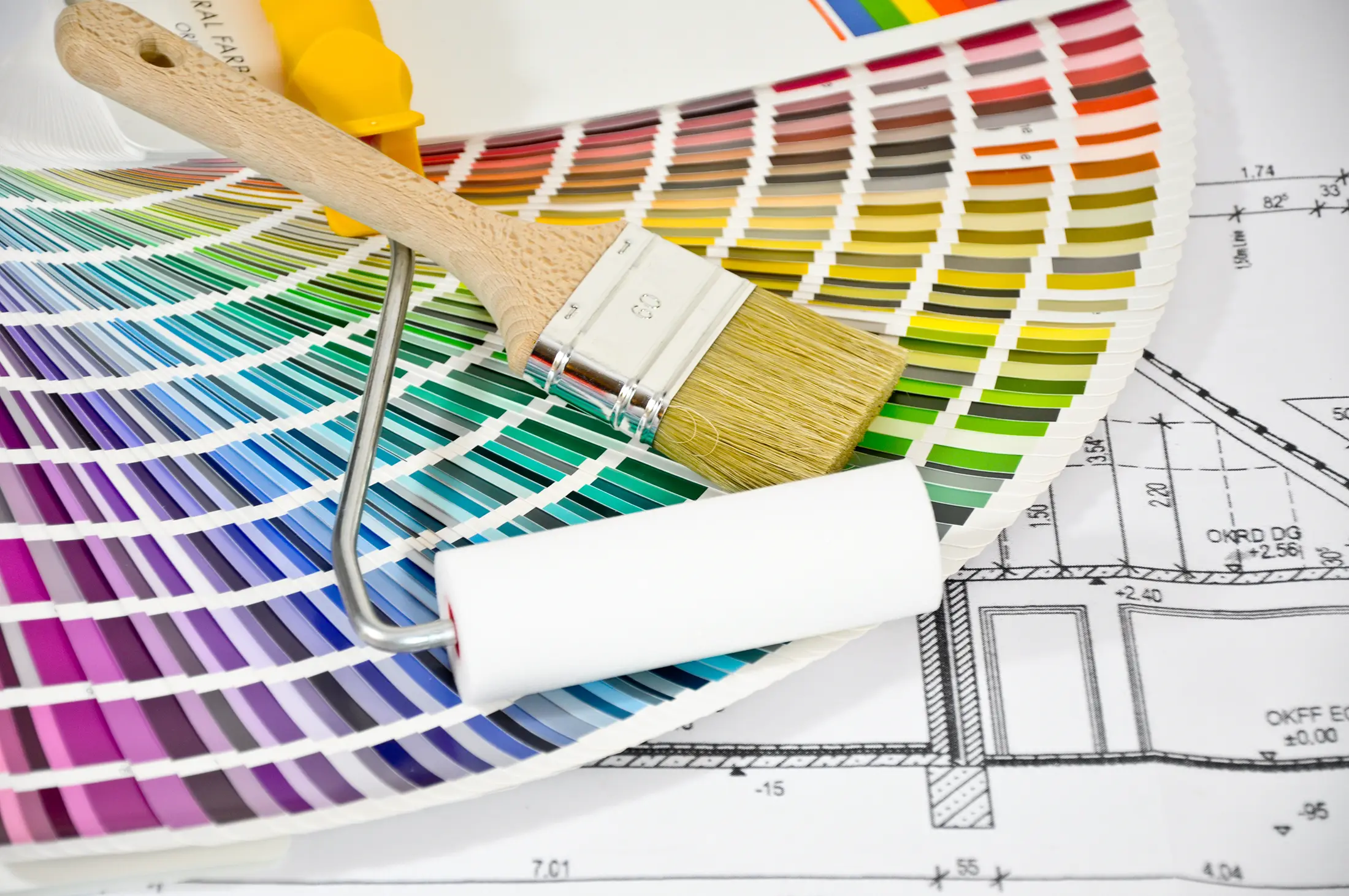 Pinsel und Farbpalette liegen auf architektonischen Plänen.
