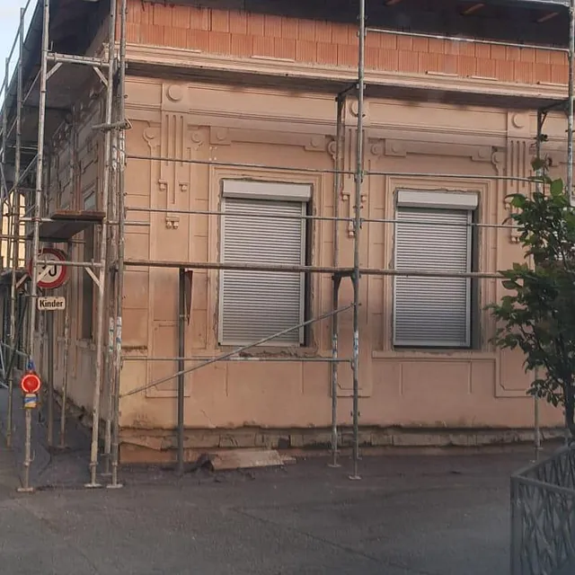 Ein Gebäude mit Gerüst an der Seite, das für Renovierungsarbeiten vorbereitet ist.