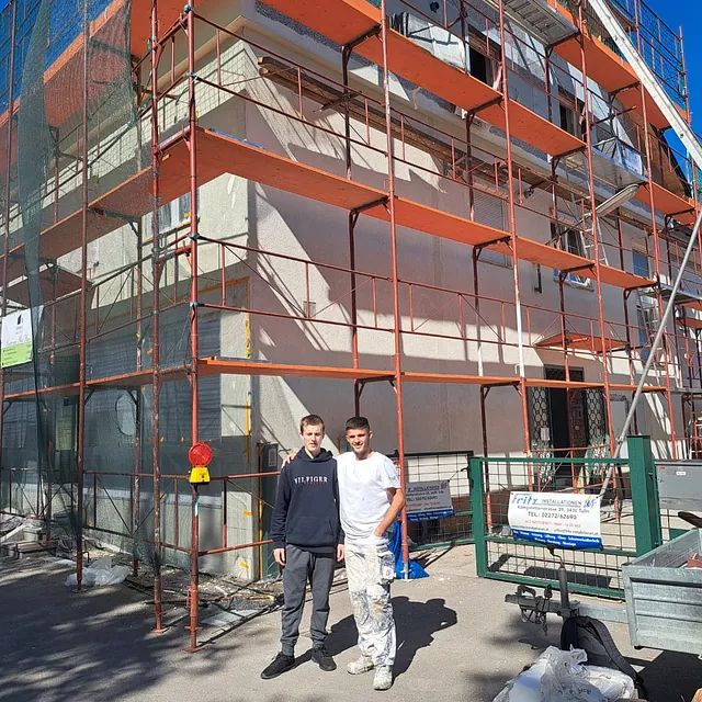 Zwei Männer stehen vor einem im Bau befindlichen Gebäude und beobachten die Arbeiten.